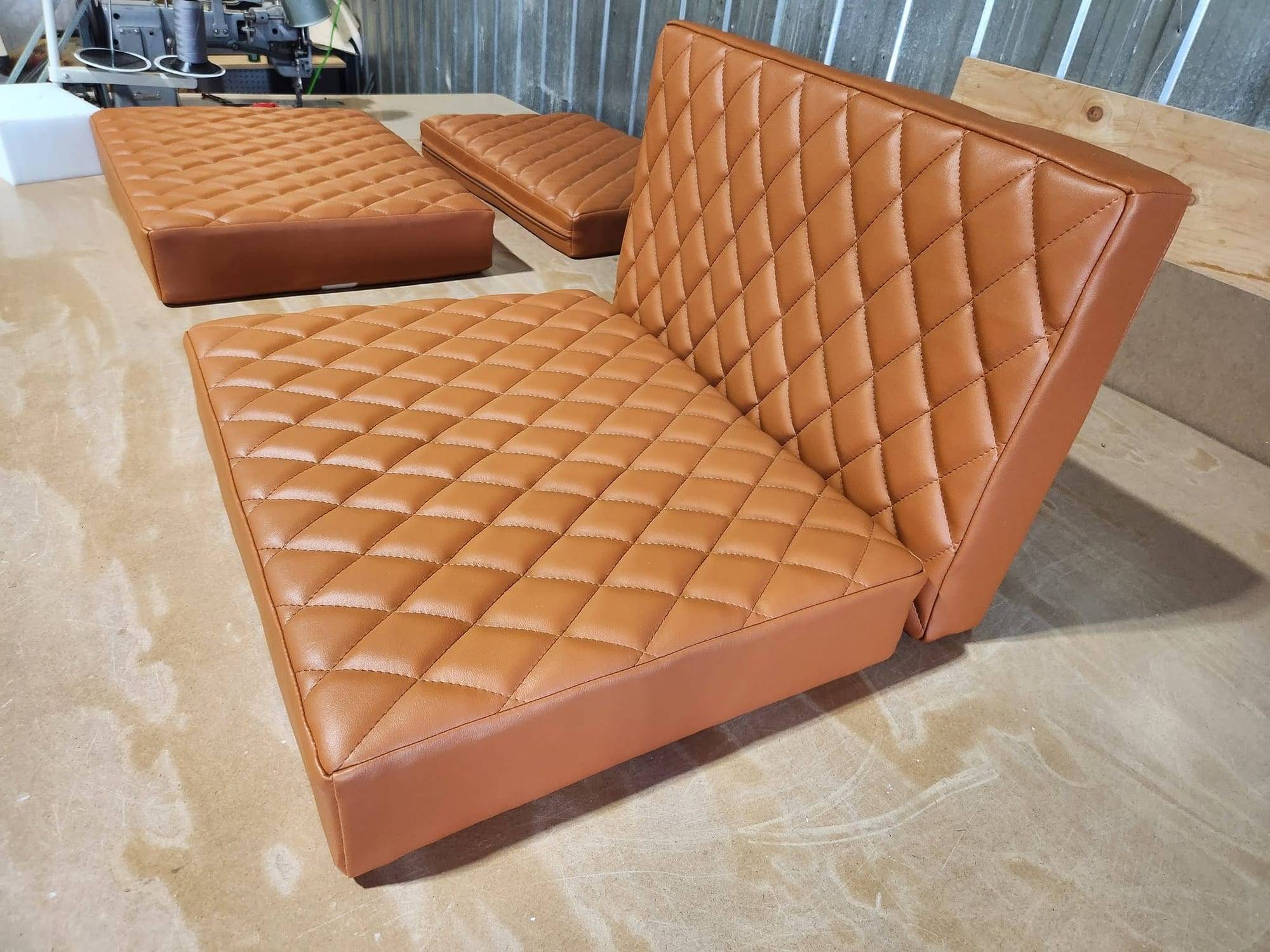 Assises et dossier de banquette en similicuir cognac piqué en losanges, sur la table de l'atelier
