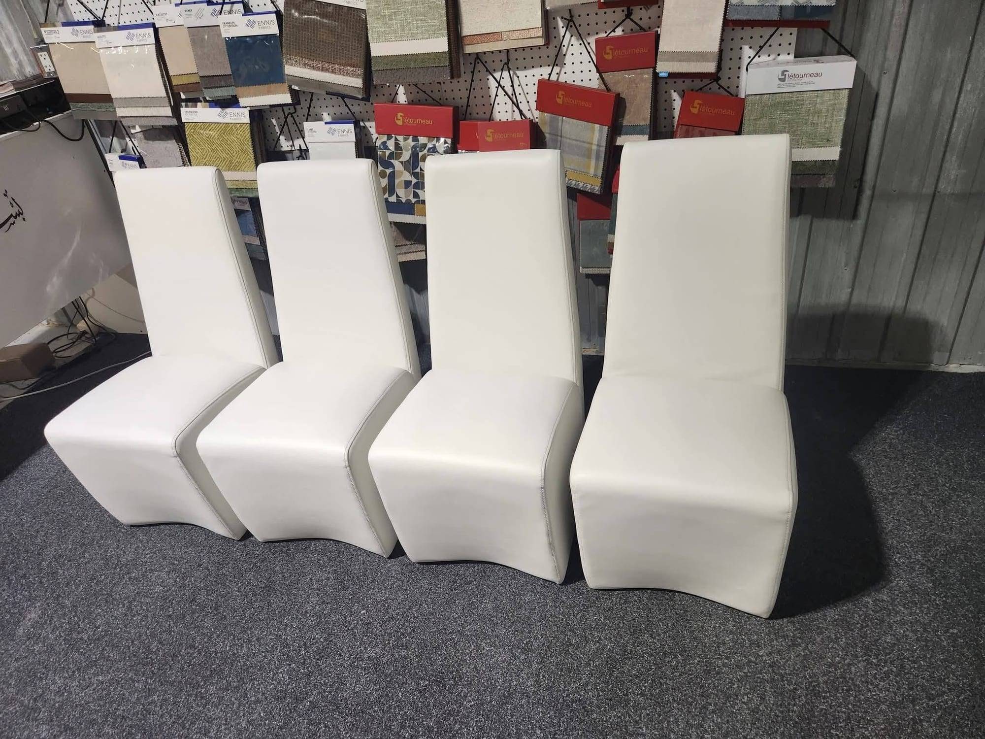 Quatre chaises à dossier haut entièrement recouvertes de similicuir blanc