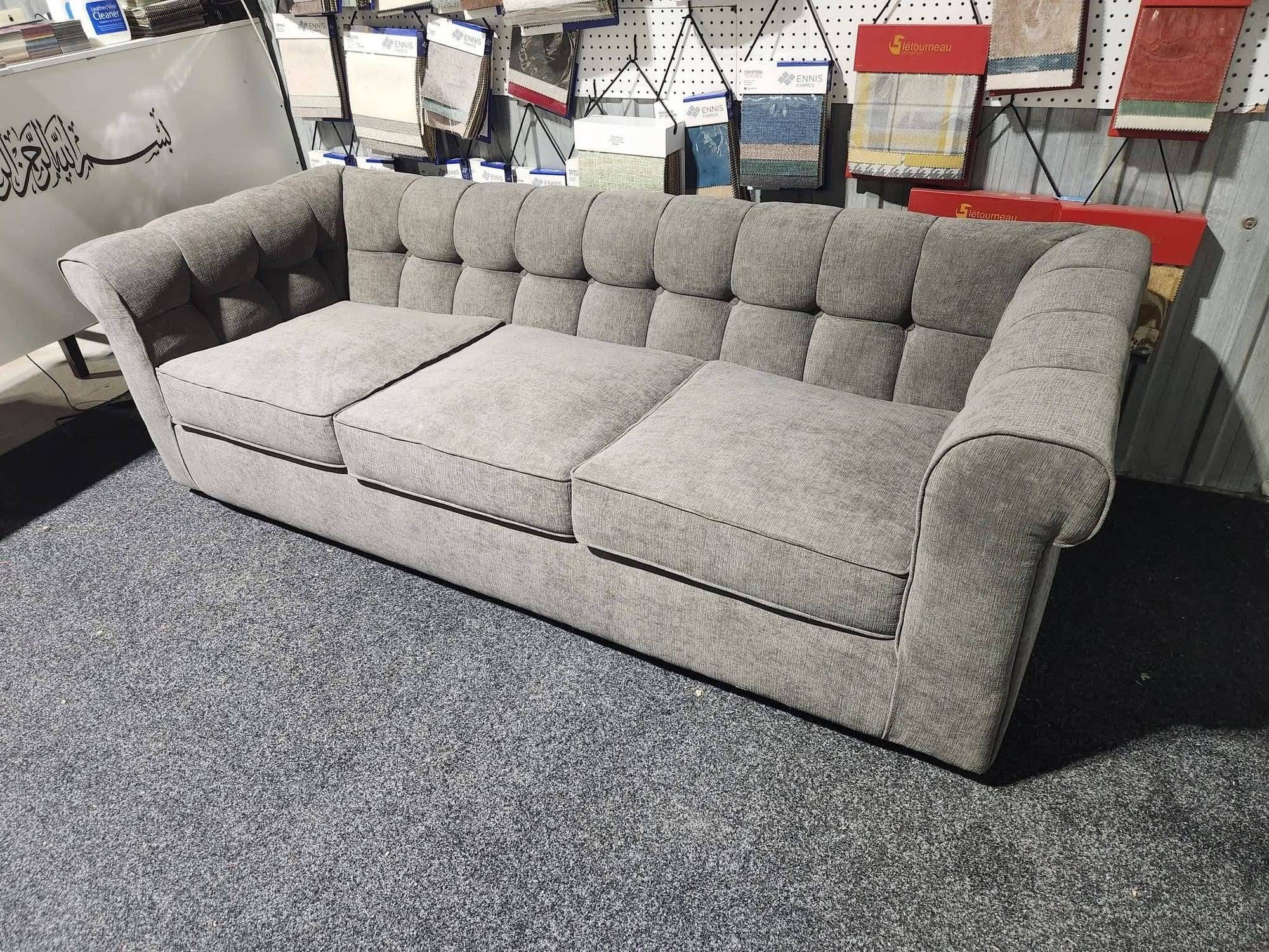 Sofa de style Chesterfield au dossier et aux bras capitonnés, recouvert d'un tissu gris