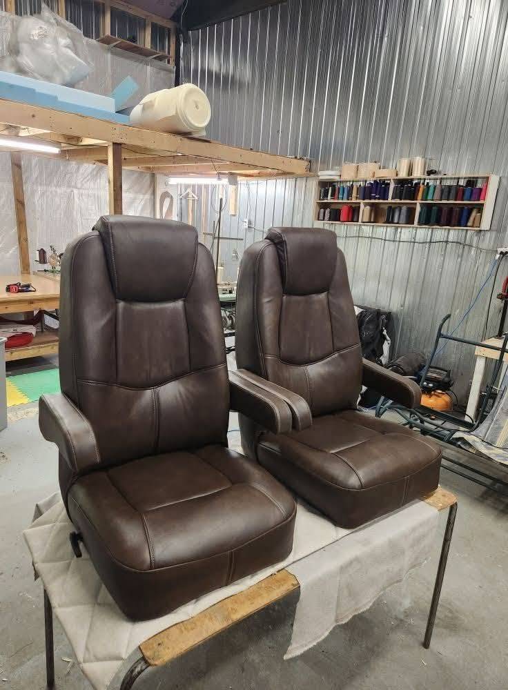 Paire de fauteuils capitaine de VR recouverts de similicuir brun, dans l'atelier