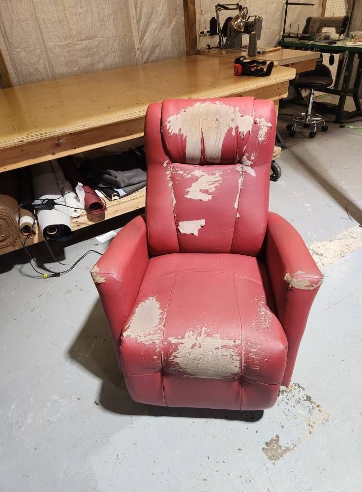 Fauteuil inclinable en similicuir rouge qui s'écaille sur le dossier et l'assise, avant le rembourrage