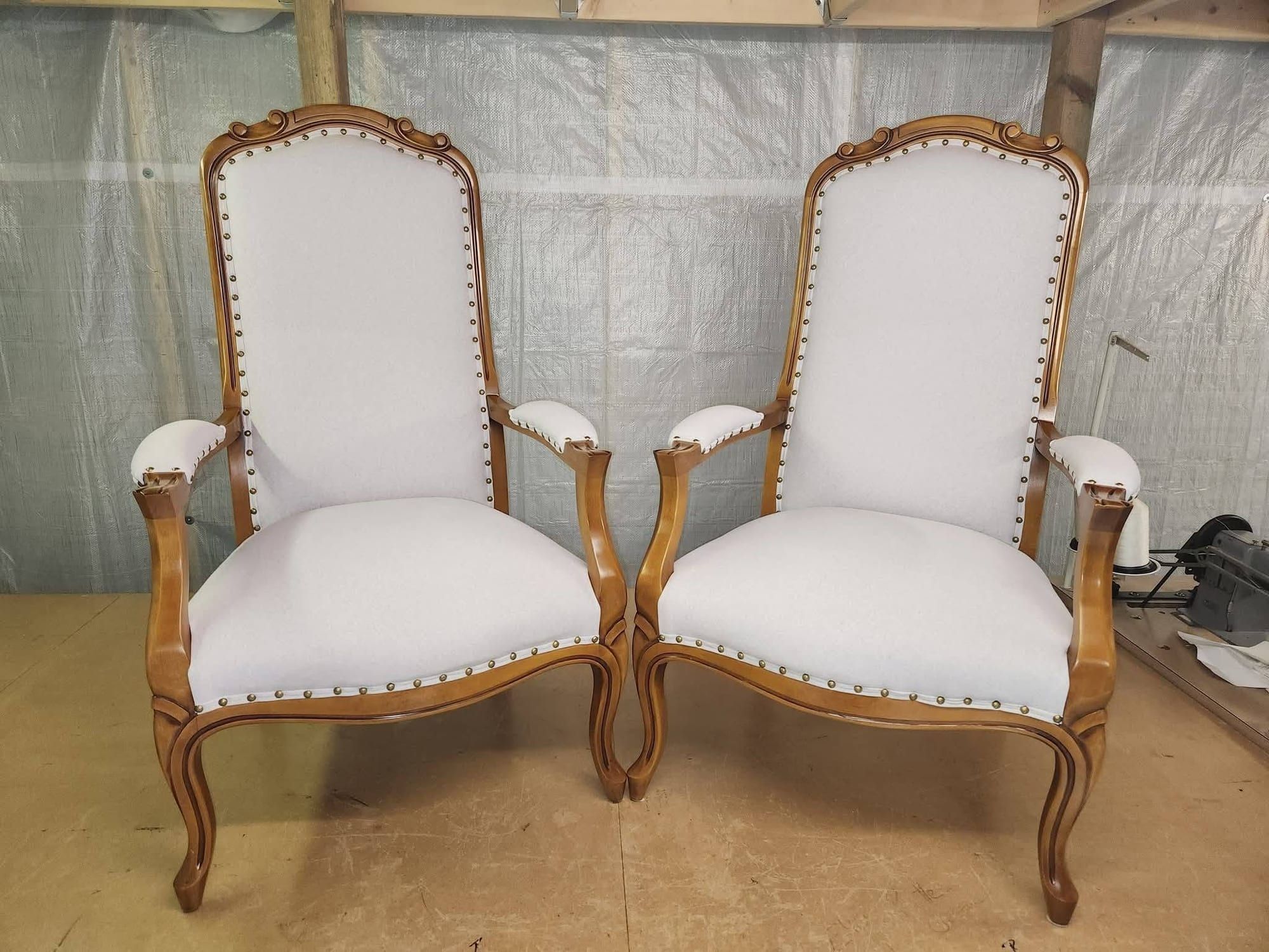Paire de fauteuils de style Louis XV regarnis d'un tissu blanc cassé et de clous décoratifs en laiton