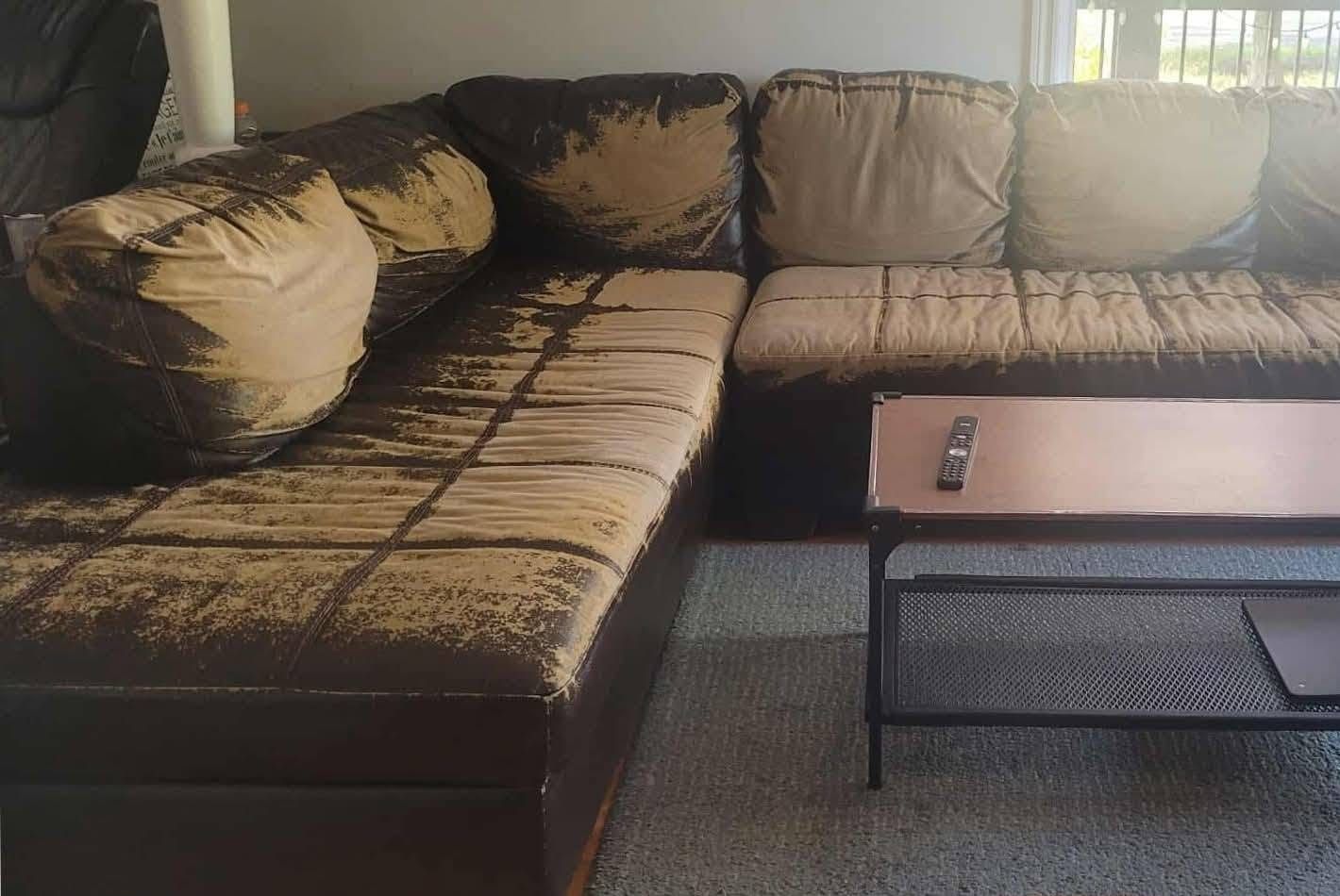 Grand sectionnel en L dont le similicuir brun pèle sur les coussins et les assises, avant les travaux